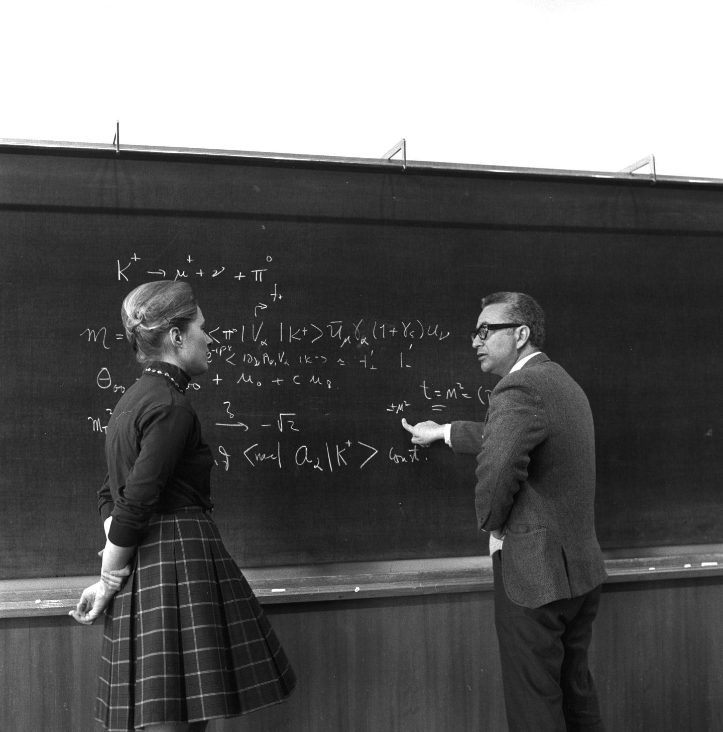 Woman and man talking by a blackboard of equations